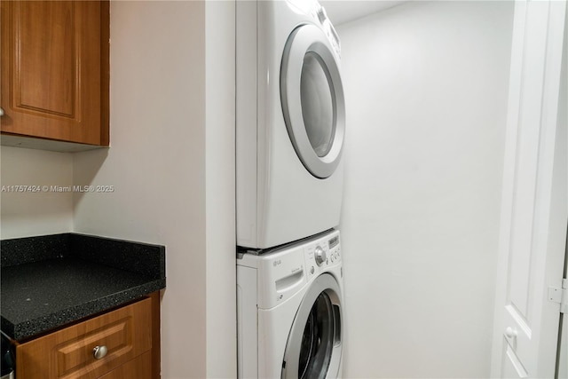 laundry area featuring stacked washing maching and dryer and cabinet space