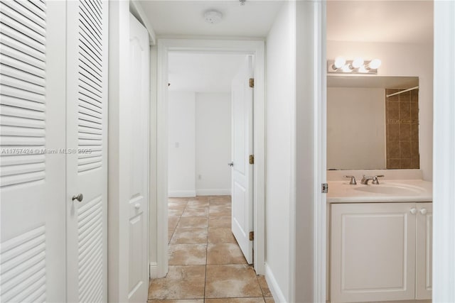 hall featuring baseboards and a sink