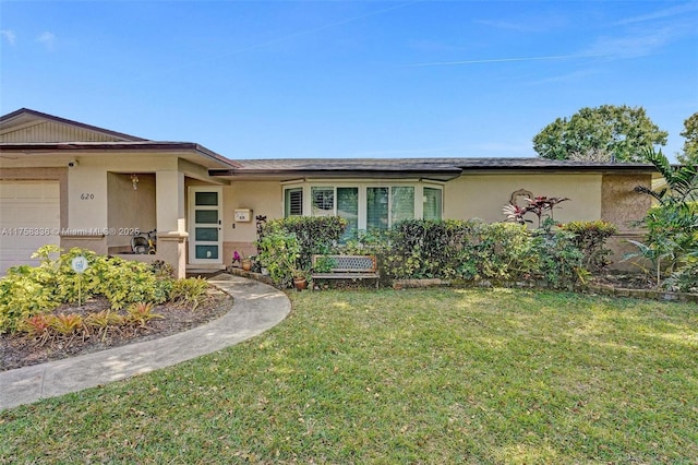 ranch-style home with stucco siding, an attached garage, and a front lawn