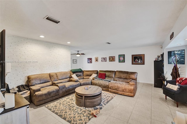 living room with light tile patterned floors, visible vents, brick wall, and a ceiling fan
