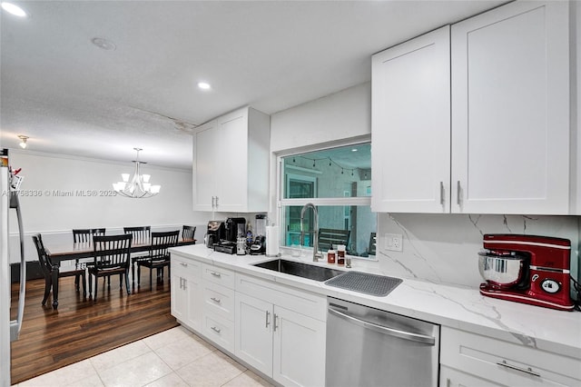 kitchen with an inviting chandelier, white cabinetry, dishwasher, and a sink