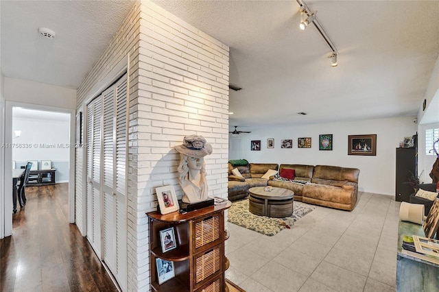 living area with rail lighting, visible vents, a ceiling fan, a textured ceiling, and tile patterned floors