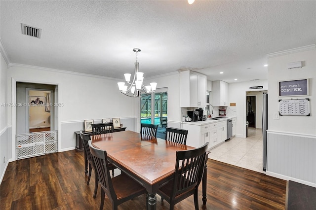 dining area featuring a textured ceiling, light wood finished floors, ornamental molding, and visible vents