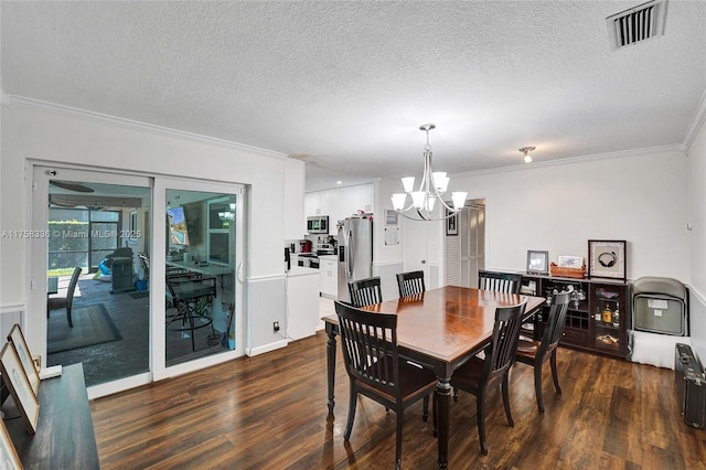 dining area featuring visible vents, dark wood-type flooring, crown molding, a textured ceiling, and a chandelier