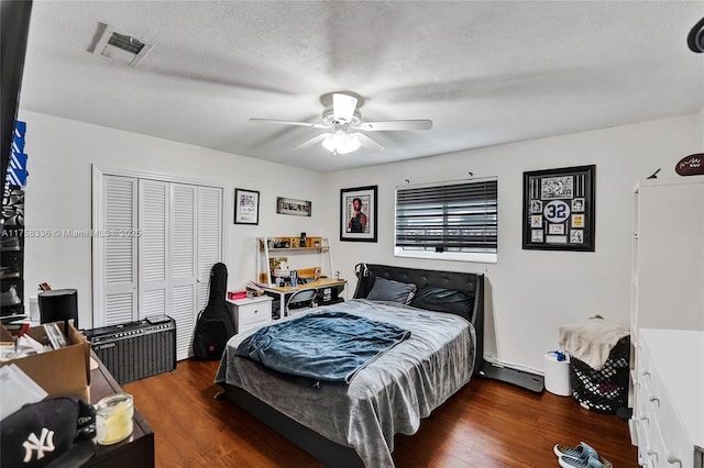 bedroom with a textured ceiling, a closet, wood finished floors, and visible vents