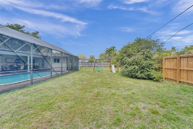 view of yard featuring a fenced in pool, a playground, glass enclosure, and a fenced backyard