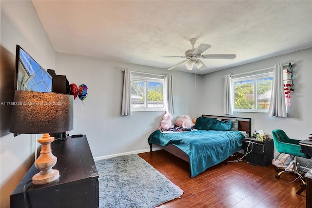 bedroom featuring multiple windows, wood finished floors, a ceiling fan, and baseboards