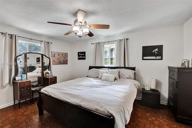 bedroom with a textured ceiling, ceiling fan, and baseboards