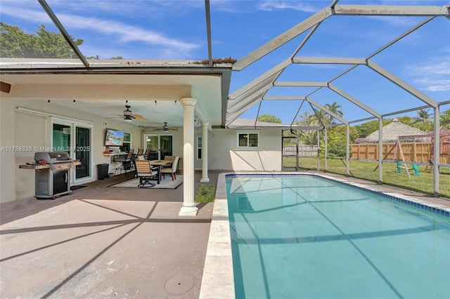 view of swimming pool featuring glass enclosure, fence, a ceiling fan, grilling area, and a patio area