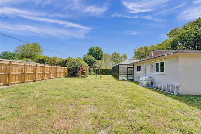 view of yard featuring fence private yard, glass enclosure, and a playground