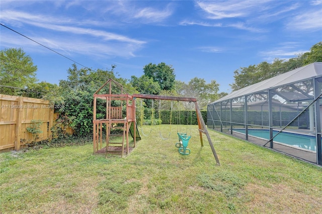 view of playground with glass enclosure, a lawn, a fenced backyard, and a fenced in pool