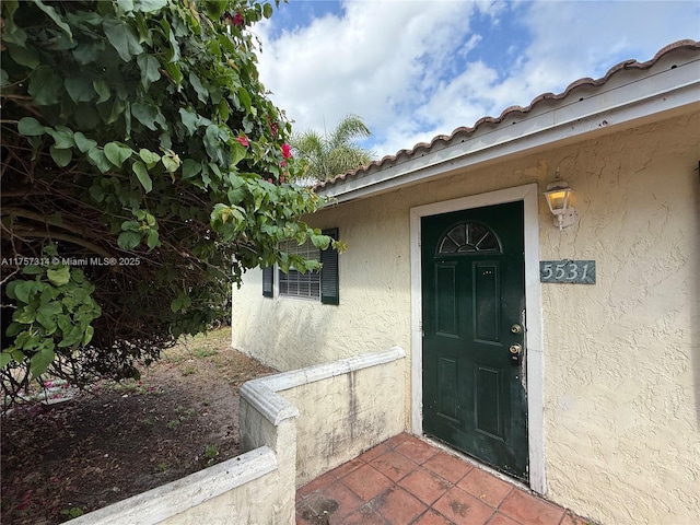 doorway to property featuring a tiled roof and stucco siding