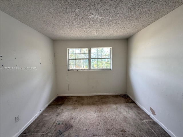 carpeted empty room featuring a textured ceiling and baseboards