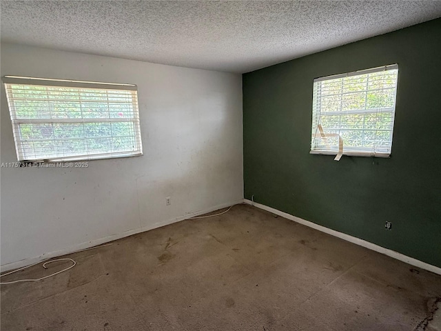 carpeted empty room with baseboards and a textured ceiling