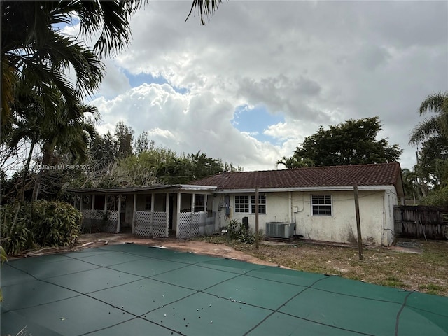 rear view of property featuring fence, central AC unit, and stucco siding