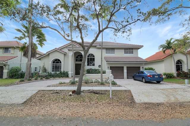 mediterranean / spanish-style home featuring an attached garage, stucco siding, concrete driveway, and a tiled roof