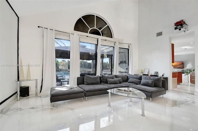 living room with marble finish floor, a high ceiling, and visible vents