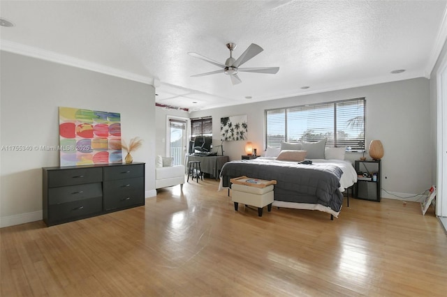 bedroom featuring ornamental molding, light wood-type flooring, a textured ceiling, and baseboards