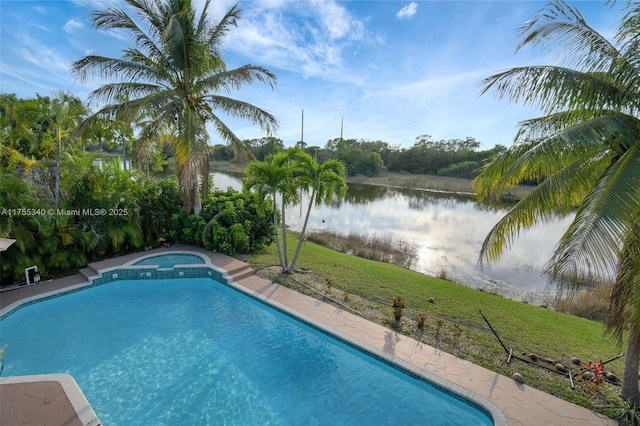 view of swimming pool with a lawn, a water view, and a pool with connected hot tub