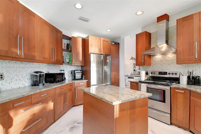 kitchen featuring light stone counters, visible vents, appliances with stainless steel finishes, a kitchen island, and wall chimney exhaust hood