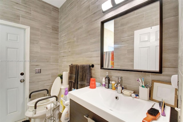 bathroom with toilet, tile walls, and vanity