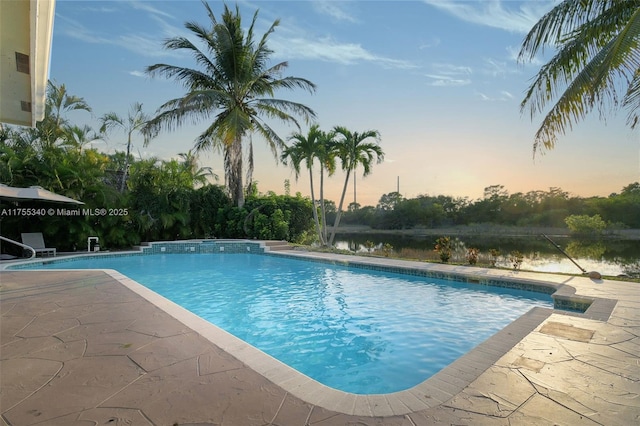 pool at dusk featuring an outdoor pool and a patio