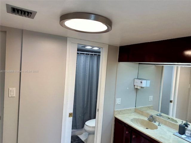 bathroom featuring curtained shower, visible vents, vanity, and toilet