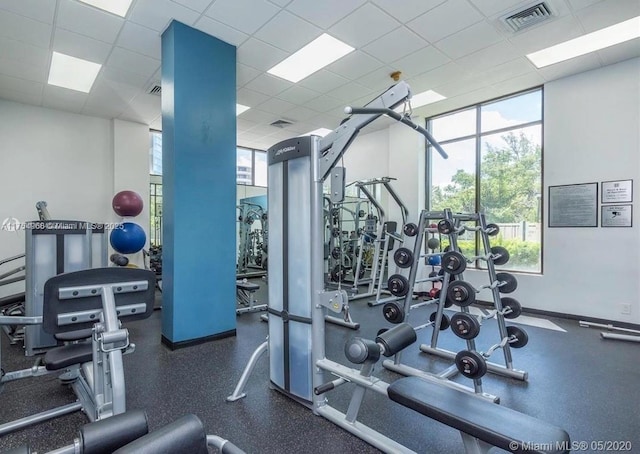 exercise room featuring a paneled ceiling, baseboards, and visible vents