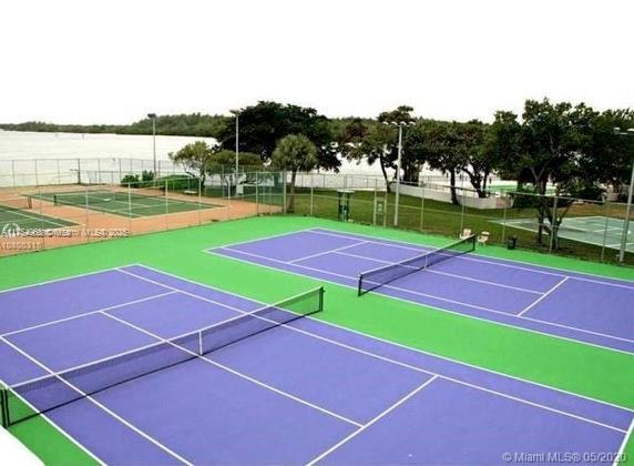 view of tennis court with community basketball court and fence