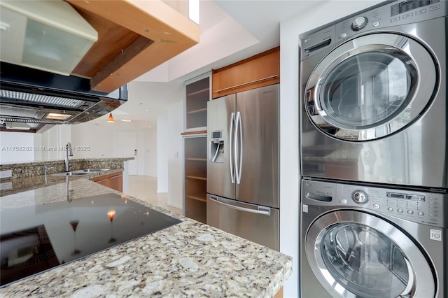 laundry room featuring a sink and stacked washer / drying machine