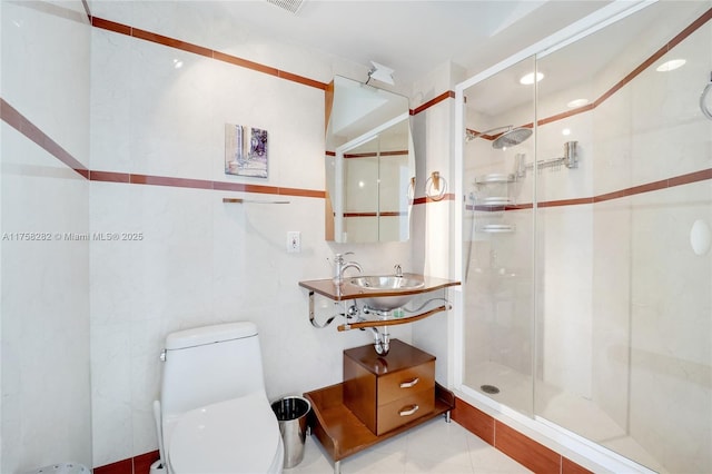 bathroom with a sink, a shower stall, toilet, and tile walls