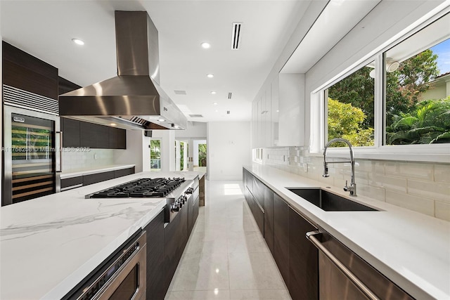 kitchen featuring a healthy amount of sunlight, island exhaust hood, stainless steel appliances, modern cabinets, and a sink