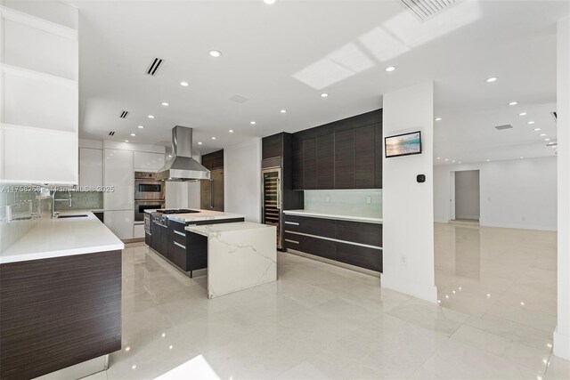 kitchen with visible vents, a kitchen island, island range hood, modern cabinets, and a sink