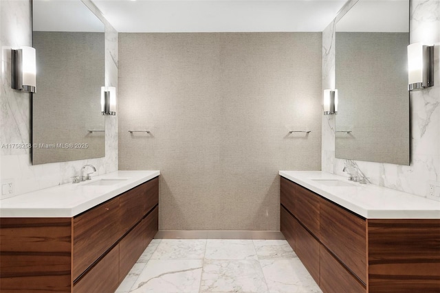 full bath with a sink, two vanities, and marble finish floor