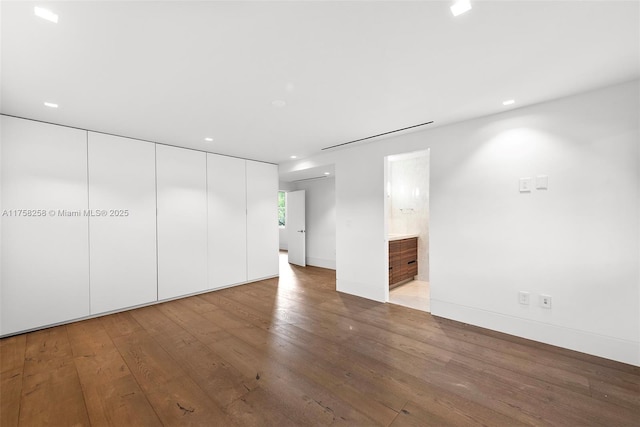 unfurnished bedroom featuring recessed lighting, baseboards, ensuite bath, and hardwood / wood-style flooring