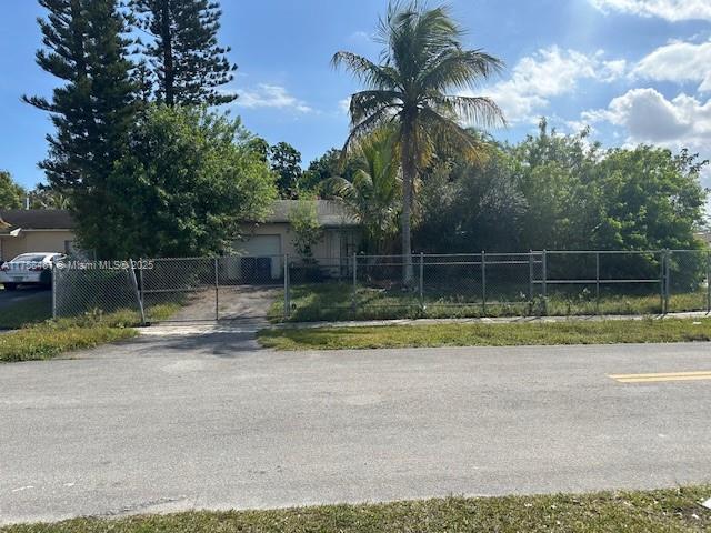 view of front of house with an attached garage, driveway, a fenced front yard, and a gate