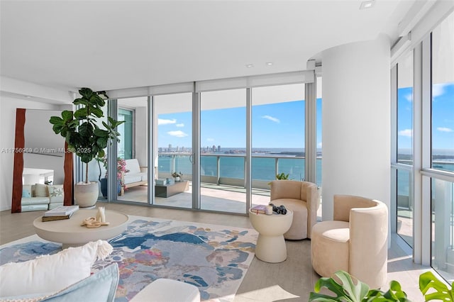 living area featuring floor to ceiling windows, a water view, and wood finished floors