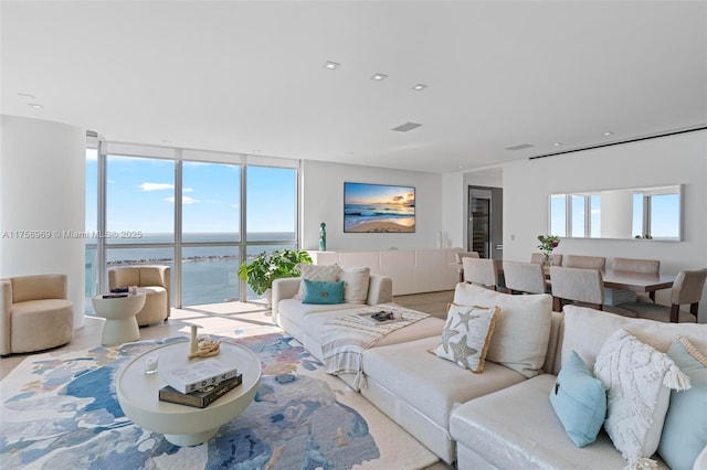 living room with expansive windows, a water view, visible vents, and recessed lighting