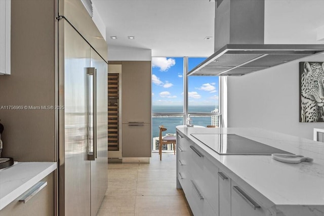 kitchen with high end refrigerator, a water view, expansive windows, black electric stovetop, and ventilation hood