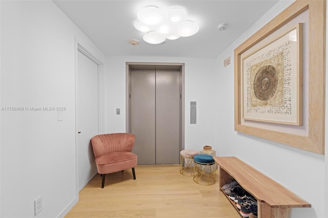 sitting room featuring elevator and wood finished floors