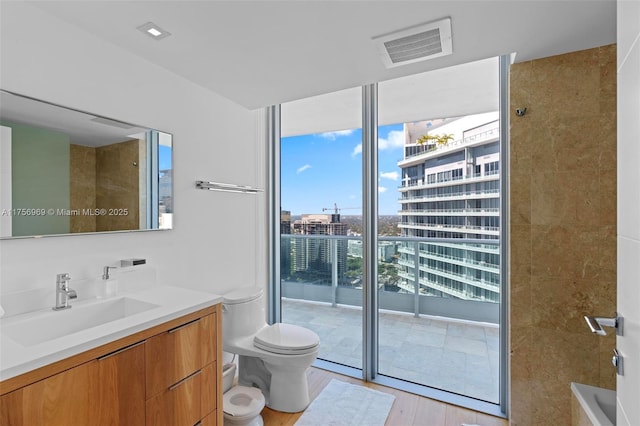 1331 Brickell Bay Dr Unit 4211, Miami, FL 33131 - bathroom featuring toilet, vanity, a wall of windows, wood finished floors, and a tub