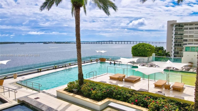 pool featuring a water view, a patio area, and fence