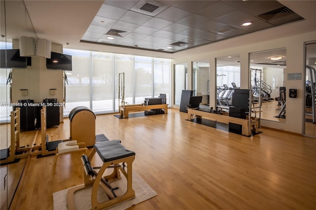 workout area featuring light wood finished floors, visible vents, and a wall of windows