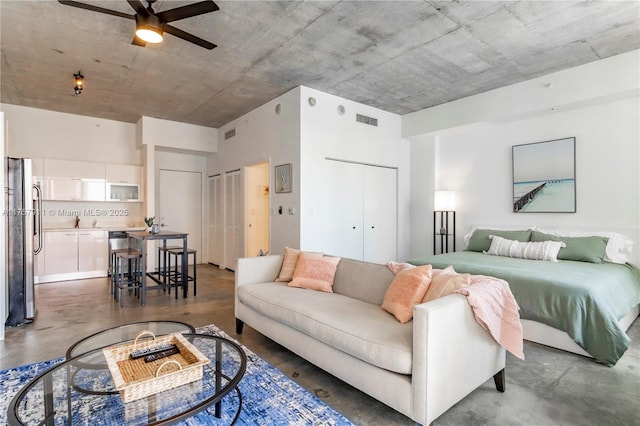 bedroom with concrete flooring, freestanding refrigerator, visible vents, and two closets