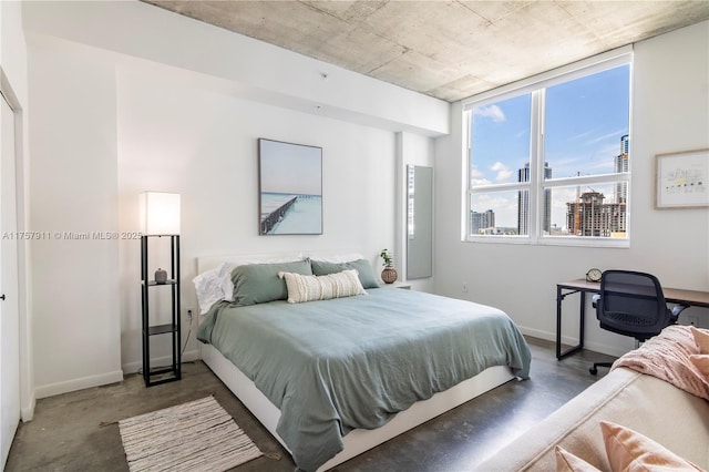 bedroom featuring concrete floors and baseboards