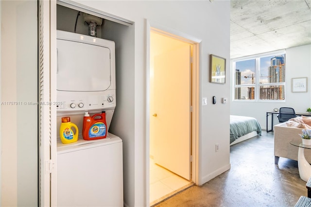 washroom with laundry area, baseboards, and stacked washing maching and dryer