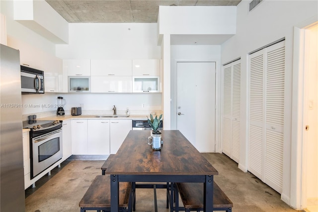 kitchen featuring visible vents, white cabinets, modern cabinets, stainless steel appliances, and a sink