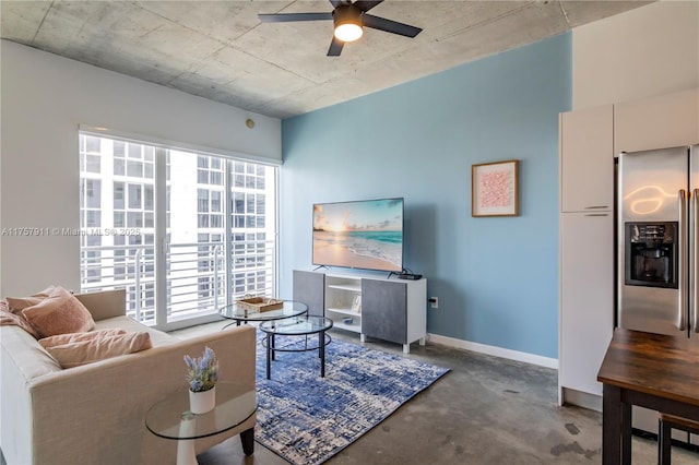 living area featuring concrete floors, a ceiling fan, and baseboards