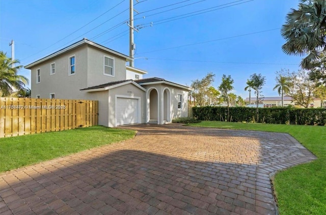 exterior space with a garage, fence, decorative driveway, a lawn, and stucco siding