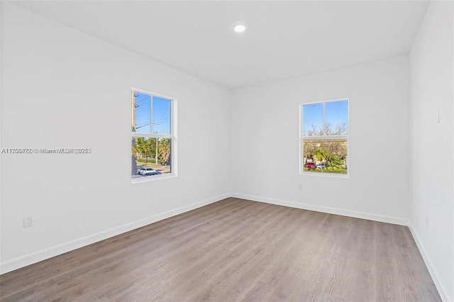 spare room with baseboards, wood finished floors, and recessed lighting